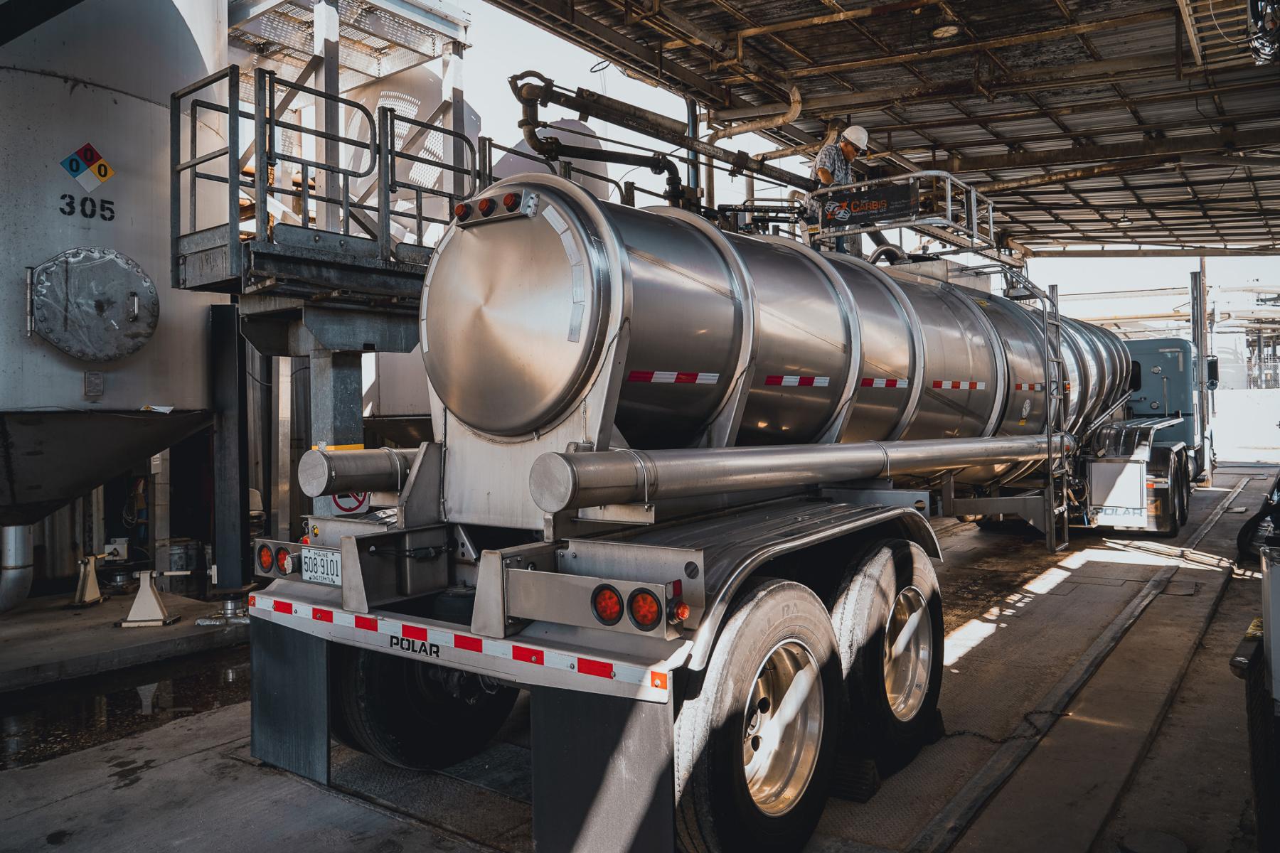 Stainless steel tanker trailer inside a Westway Feed Products loading facility during liquid feed loading operations.